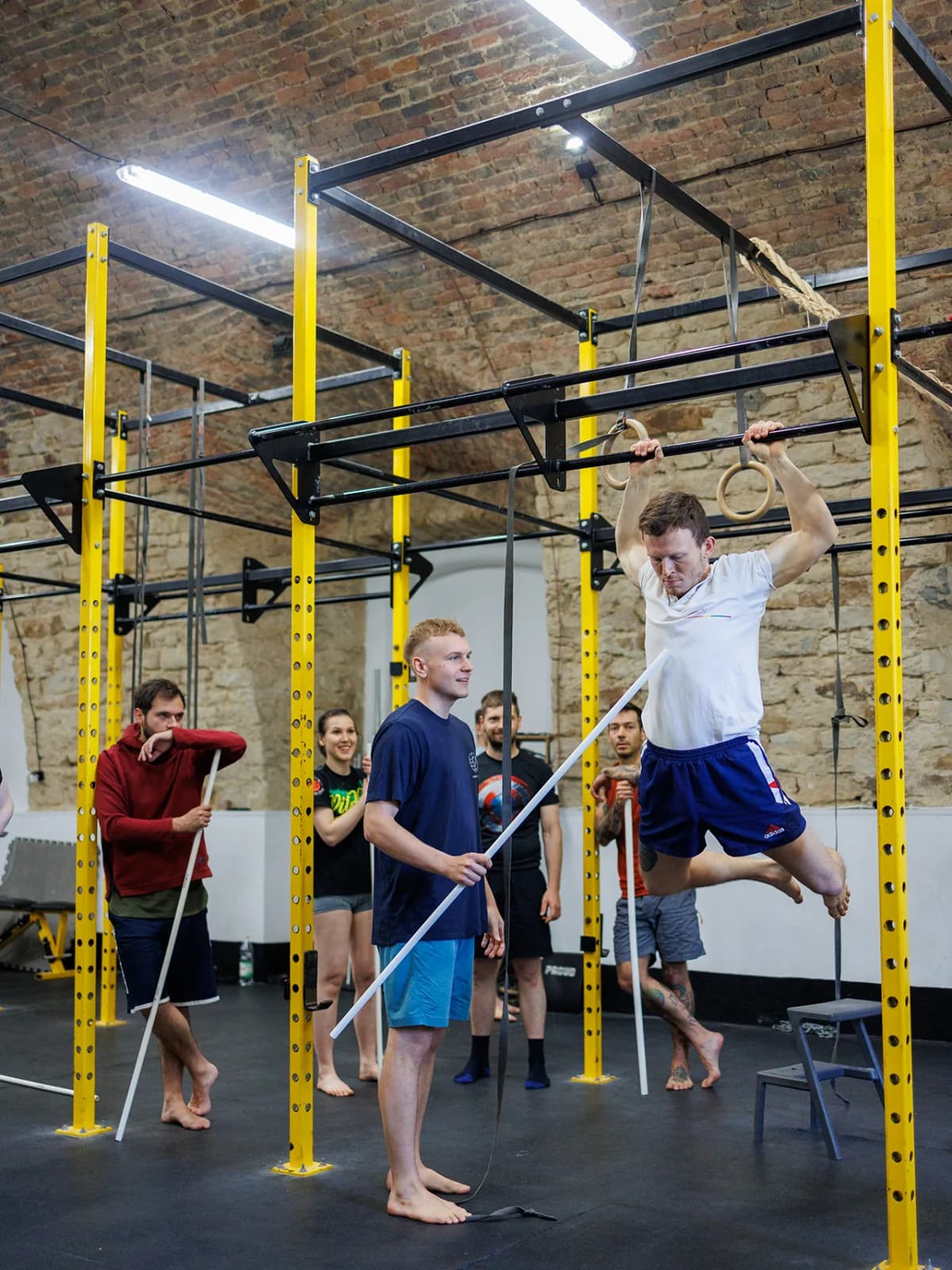 Filip coaching an athlete through a suspended-ring strength task during a practical workshop